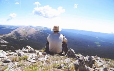 dude sitting on top of a mountain overlooking a valley, looks like someone who probably does some freelancing