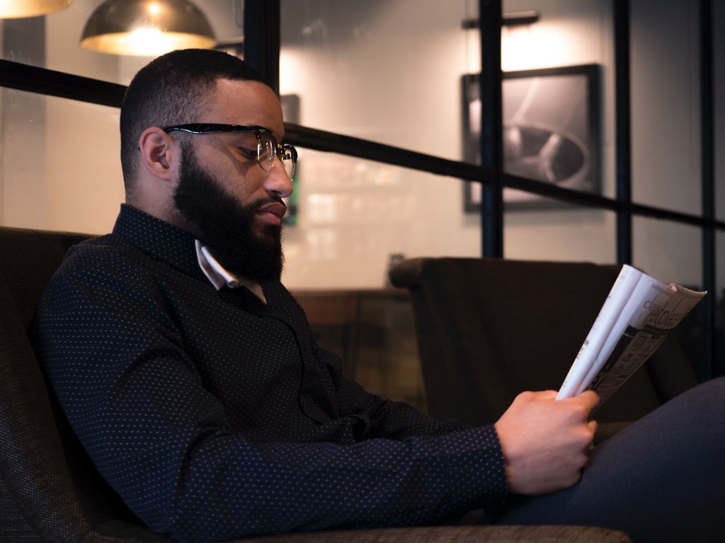 Man with glasses reading a magazine