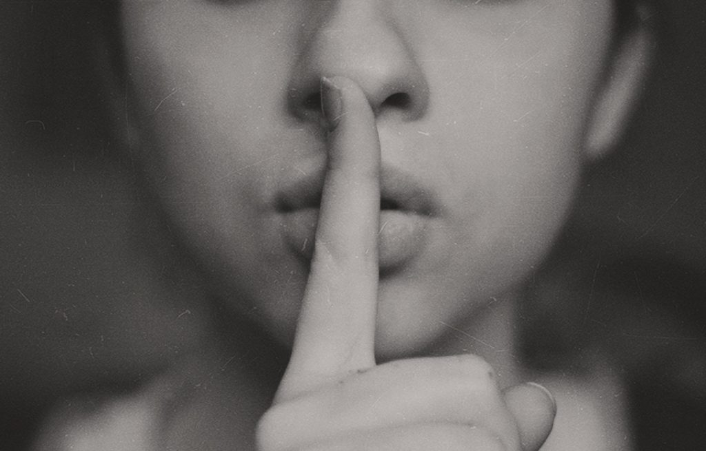 photo of a woman holding her finger in front of her mouth in a 'shhh...' gesture