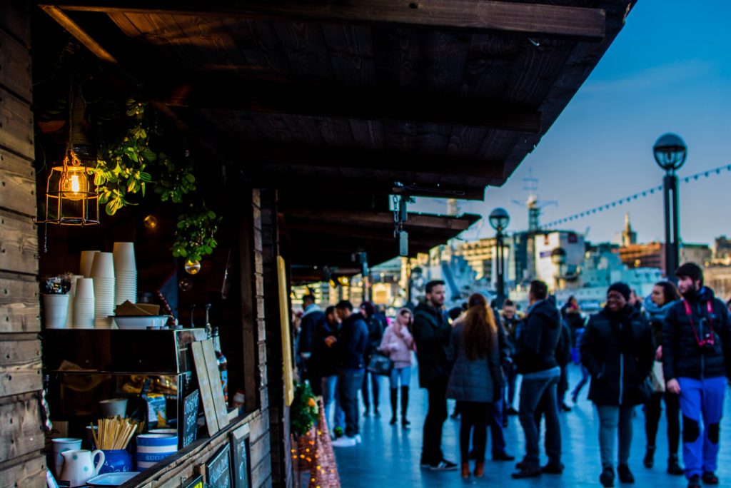 photo of passersby checking out vendor stalls near a waterfront