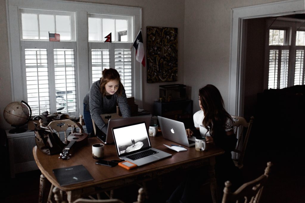 photo of two women working on laptops around a dining room table