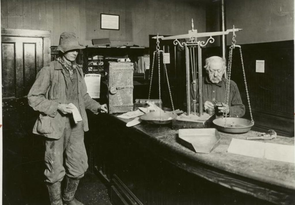 photo from new york public library digital collection showing a gold miner getting his latest haul weighed