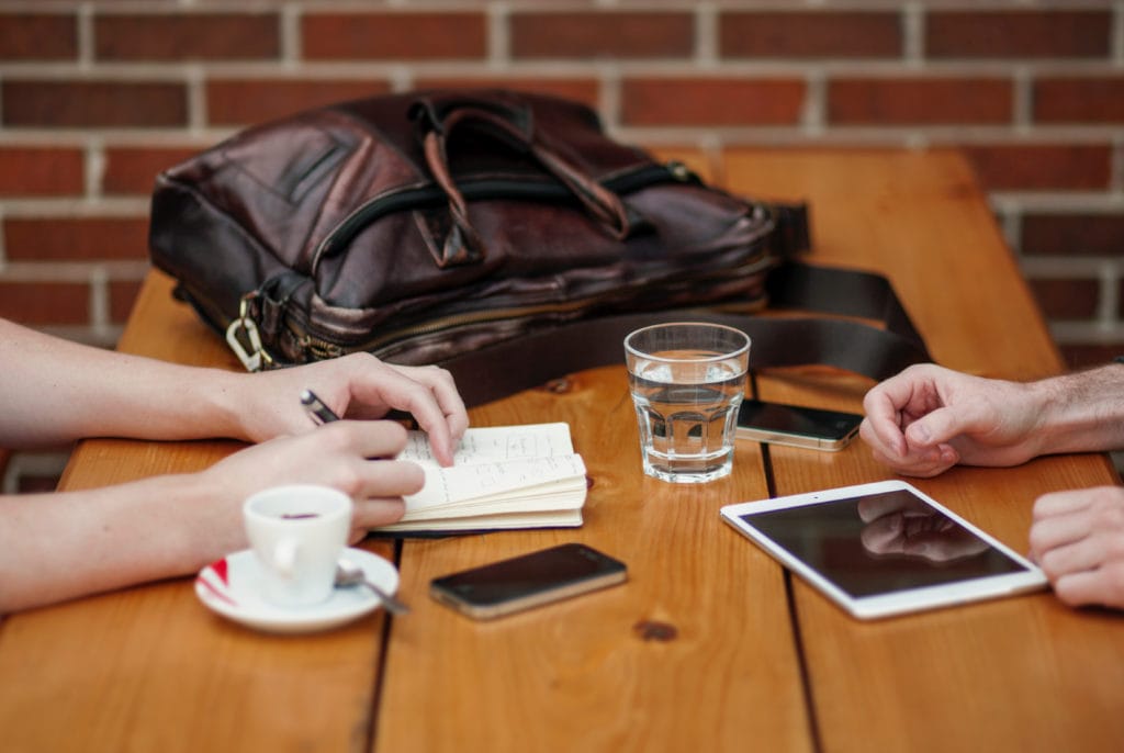 photo of two people's hands working across a table, looks like one is interviewing the other