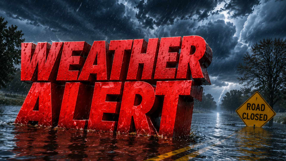 A dramatic scene showing massive red 3D lettering that reads 'WEATHER ALERT' partially submerged in a flooded road during a storm. In the background, there is a yellow diamond-shaped road sign that reads 'ROAD CLOSED'. The sky is dark and stormy with lightning strikes in the distance, and heavy rain is falling over the flooded street and surrounding trees.