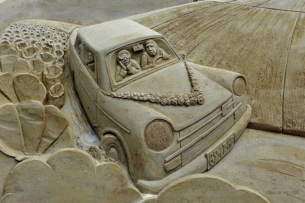 Zandsculptuur van trouwauto