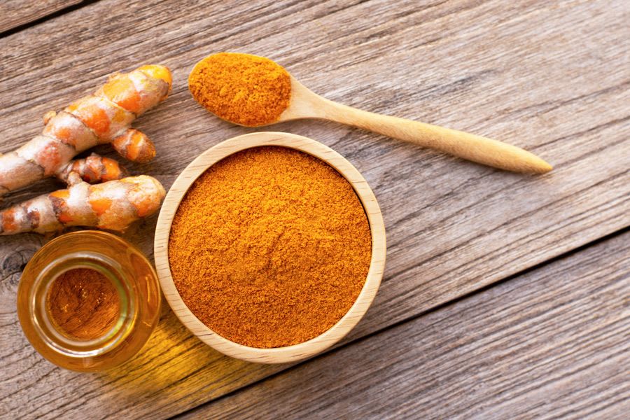 racine de curcuma et poudre sur une table en bois
