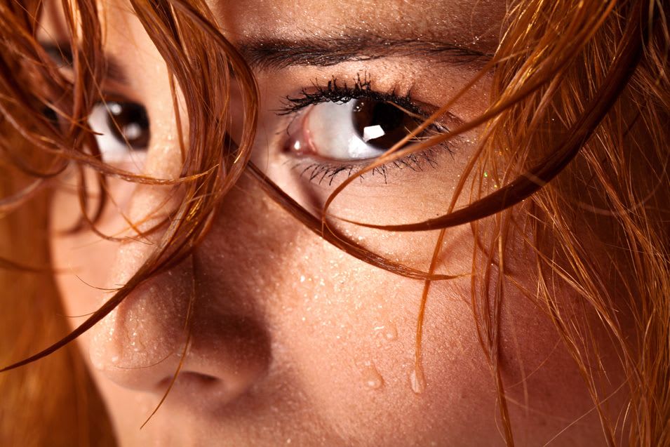 femme rousse qui a des gouttes de sueurs sur le visage.