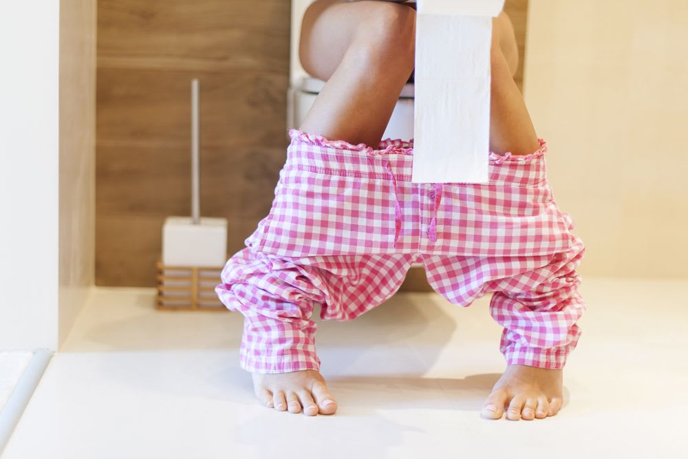 femme aux toilettes qui semblent ressentir des douleurs