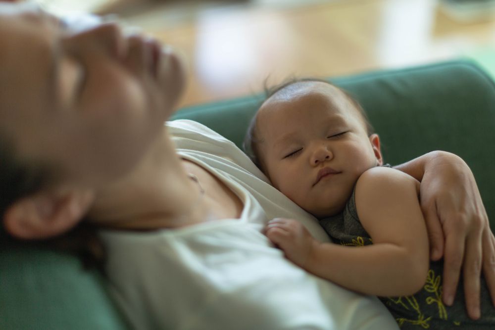 mère épuisée portant son enfant endormi