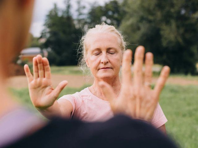 Femme pratiquant un mouvement lent de qi gong en extérieur