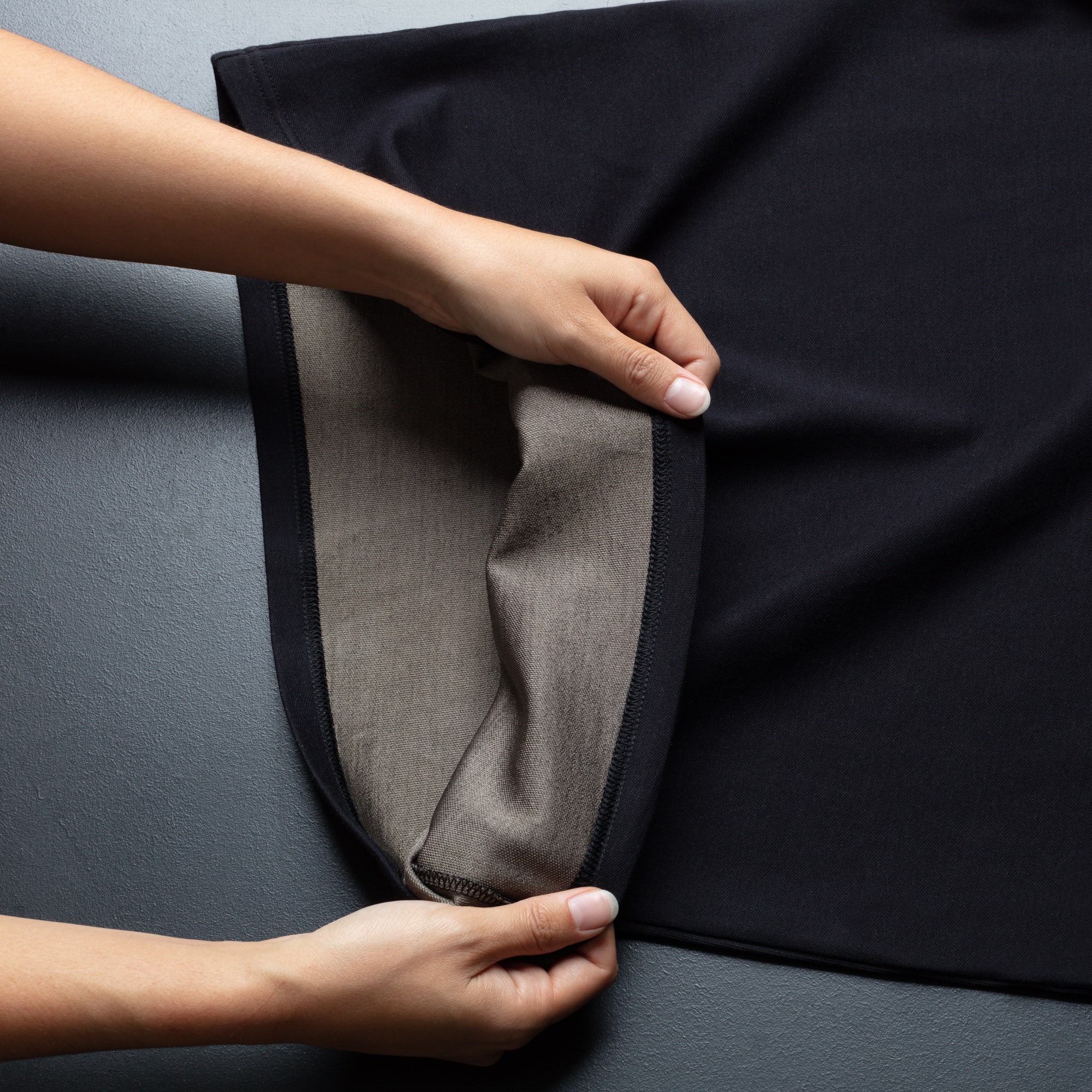 Two hands stratching the fabric to illustrate how soft and flexible the fabric is.