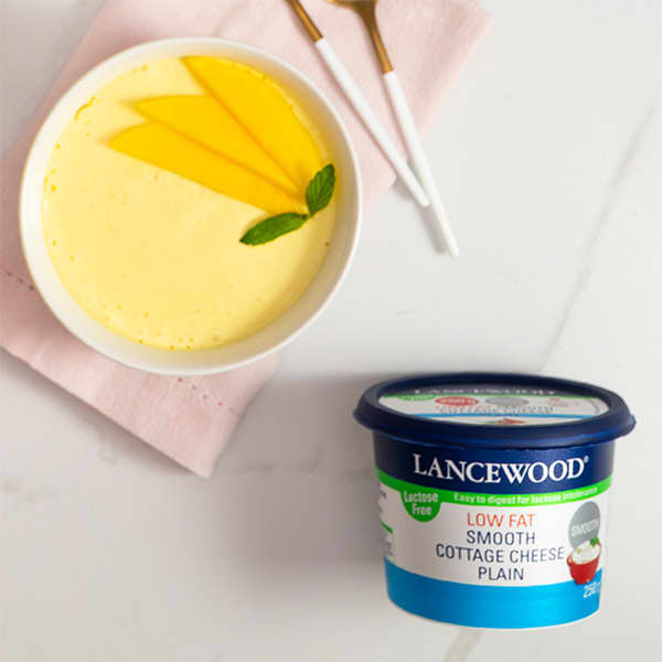 Creamy mango protein pudding made with LANCEWOOD® lactose free cheese, topped with fresh mango slices and mint