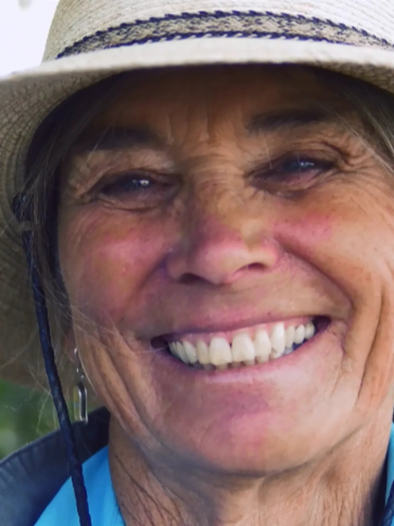 Close-up of a woman wearing a brimmed hat smiling at the camera