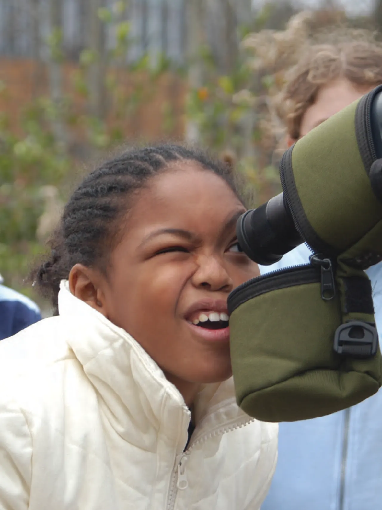Children standing around a telescope with one of them looking into the scope.