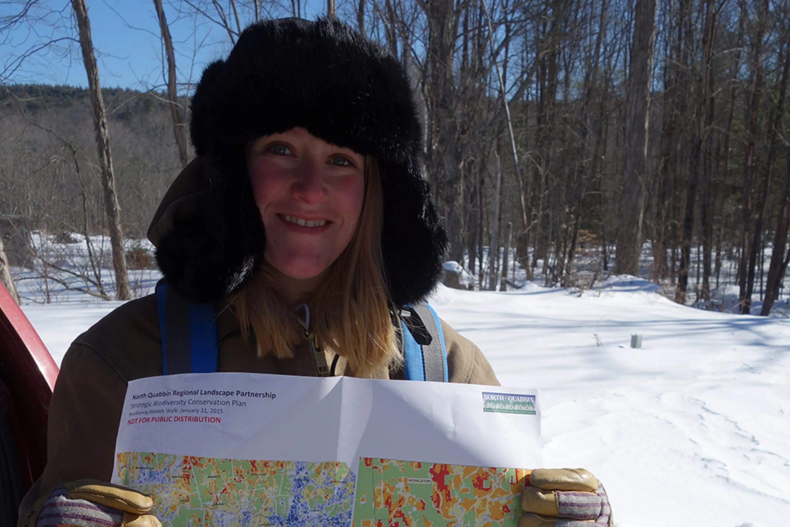 Woman wearing a snow hat holding a map up smiling at the camera