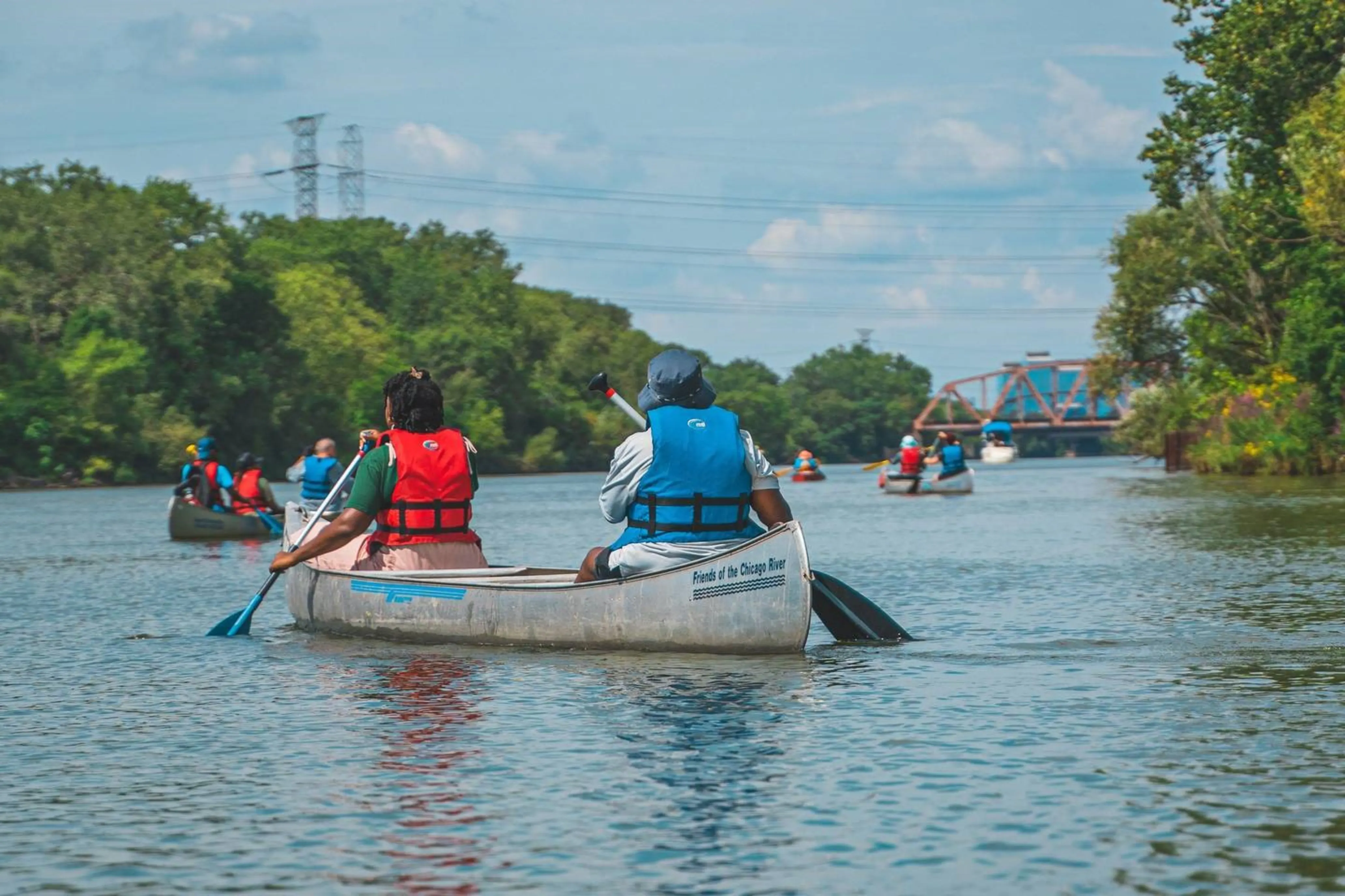 Black youths paddle a metal canoe along a tree-lined river outside Chicago.
