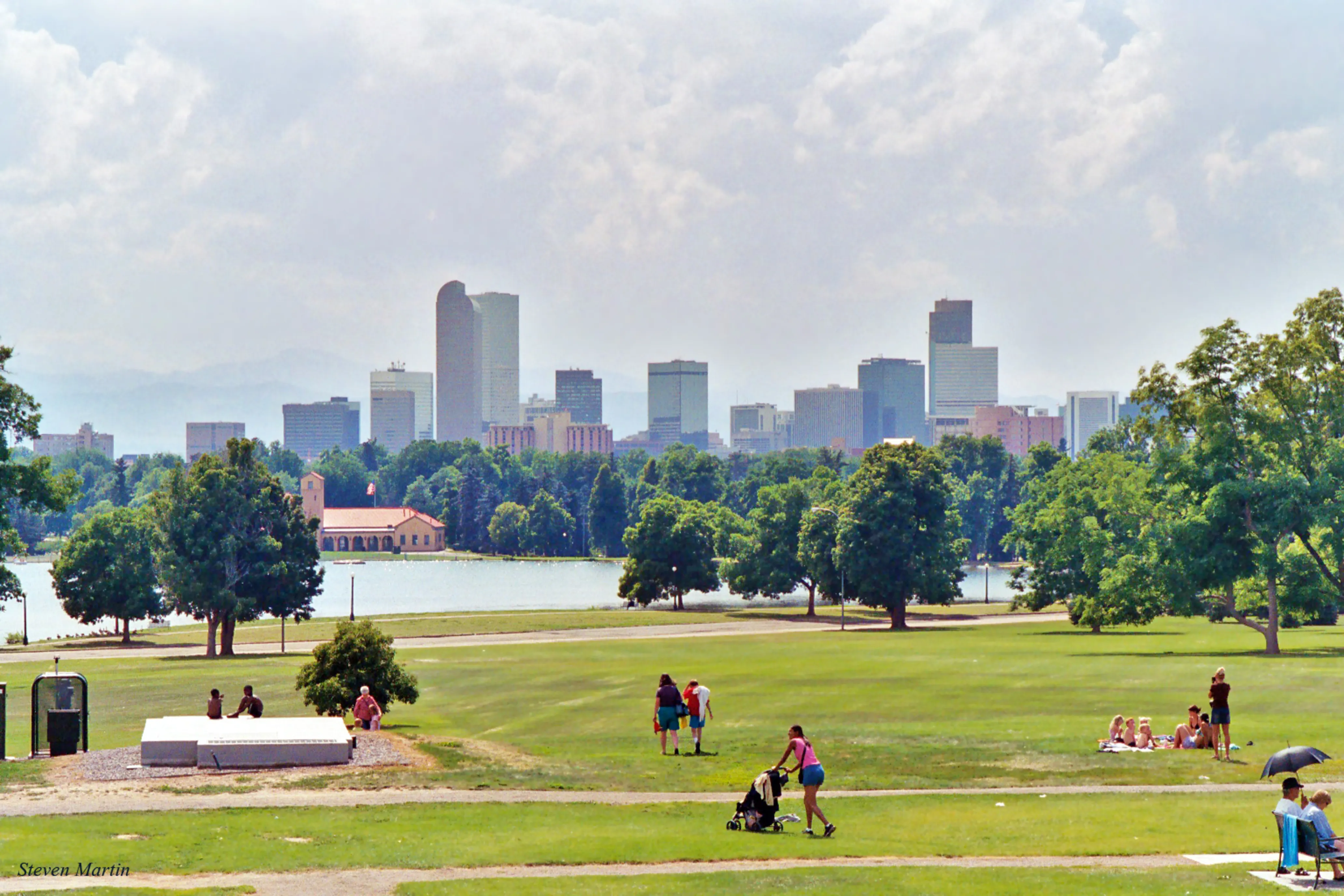 People walking around a park in Colorado with a lake