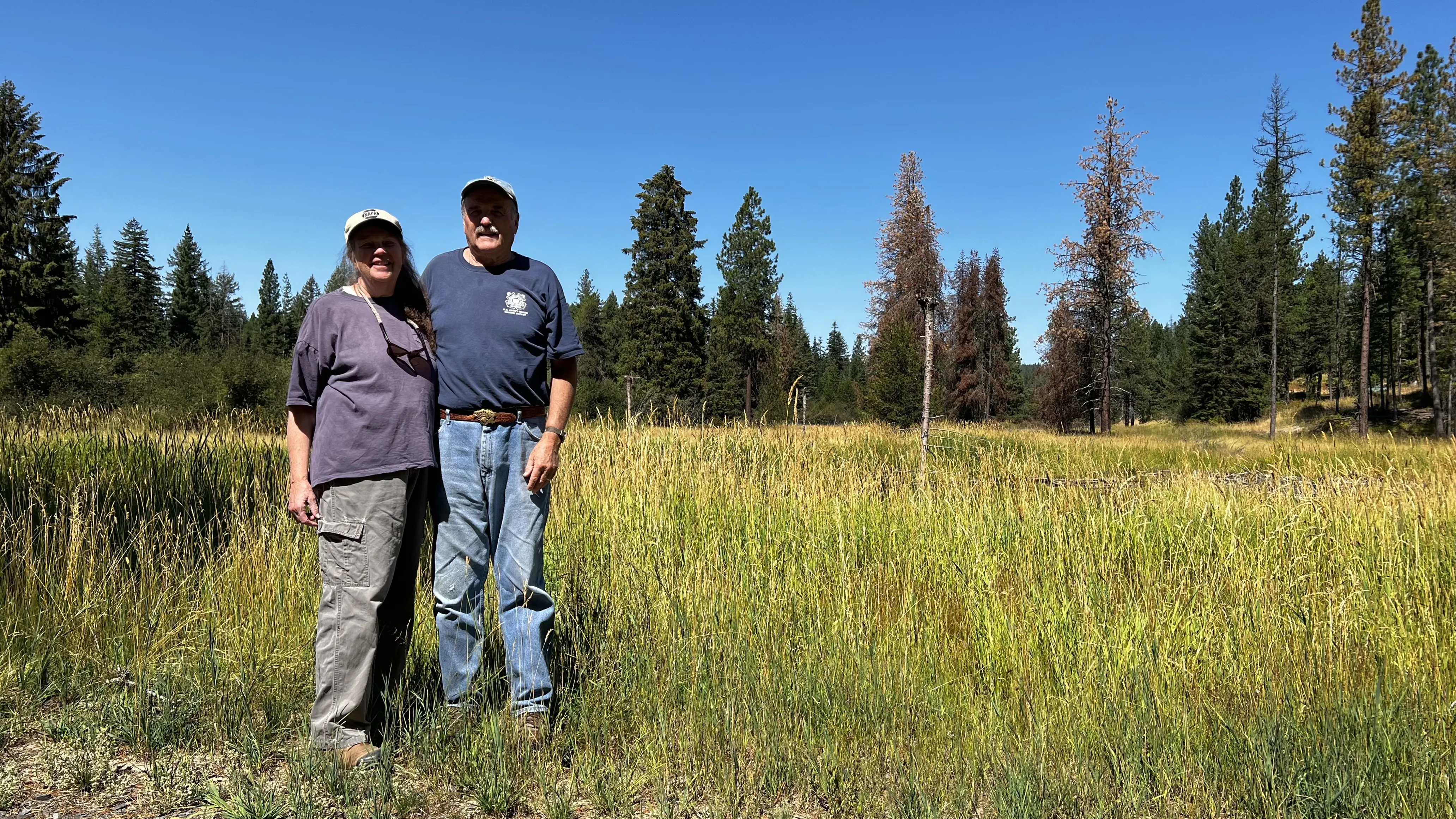 Two people in working clothes standing in a field.