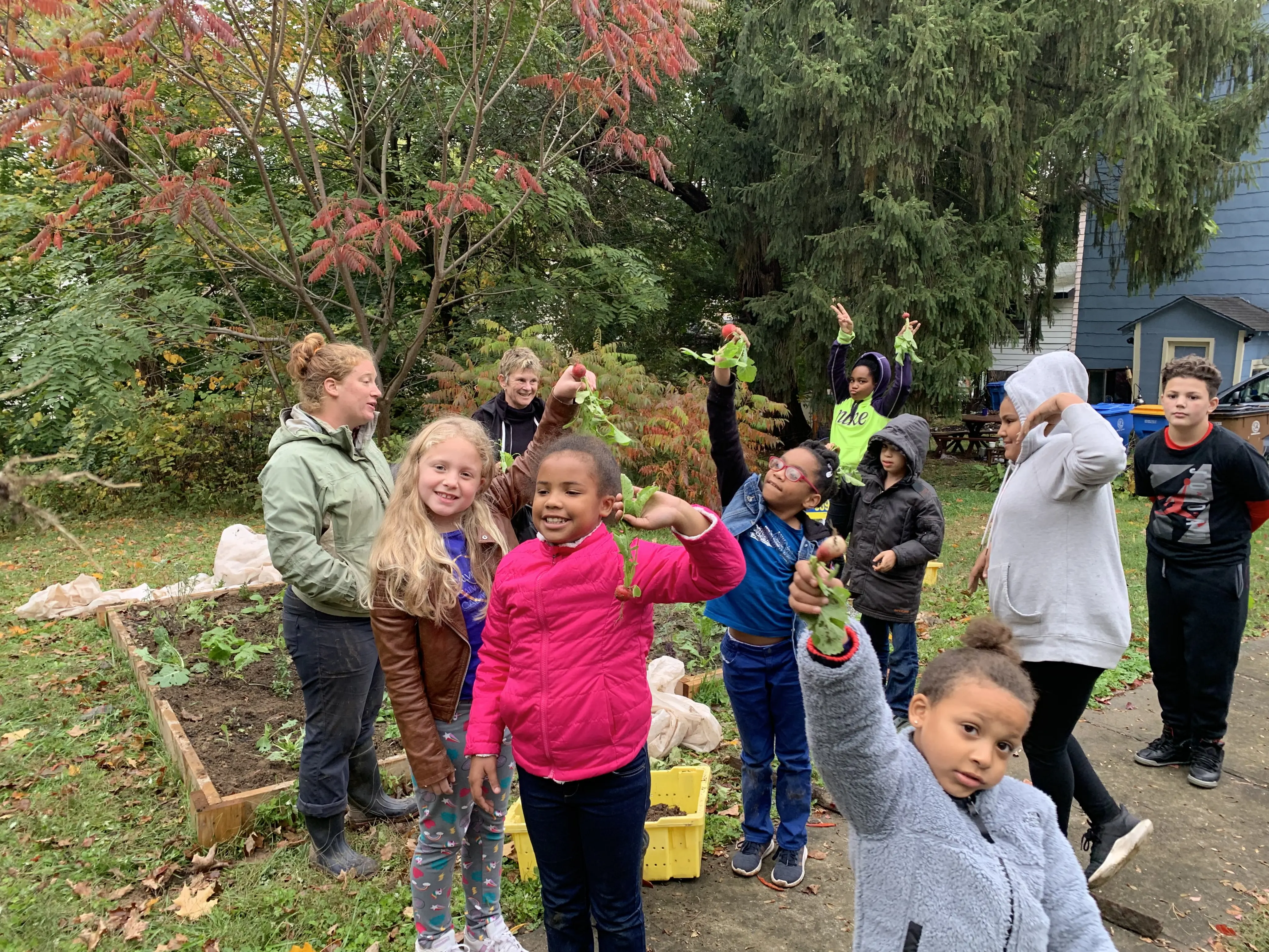 Nine children hold vegetables they harvested