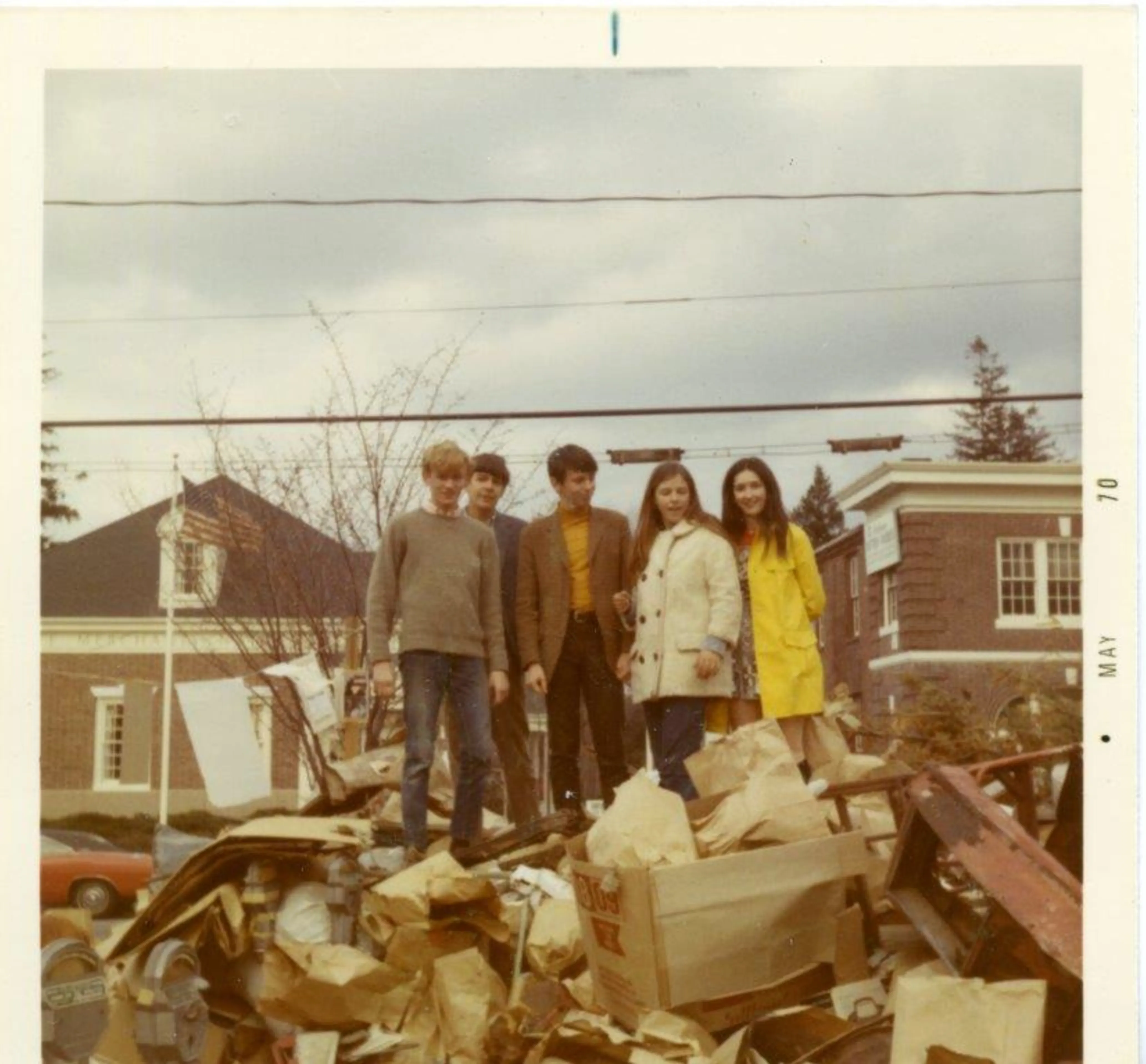 Five teenagers stand atop a pile of garbage they collected
