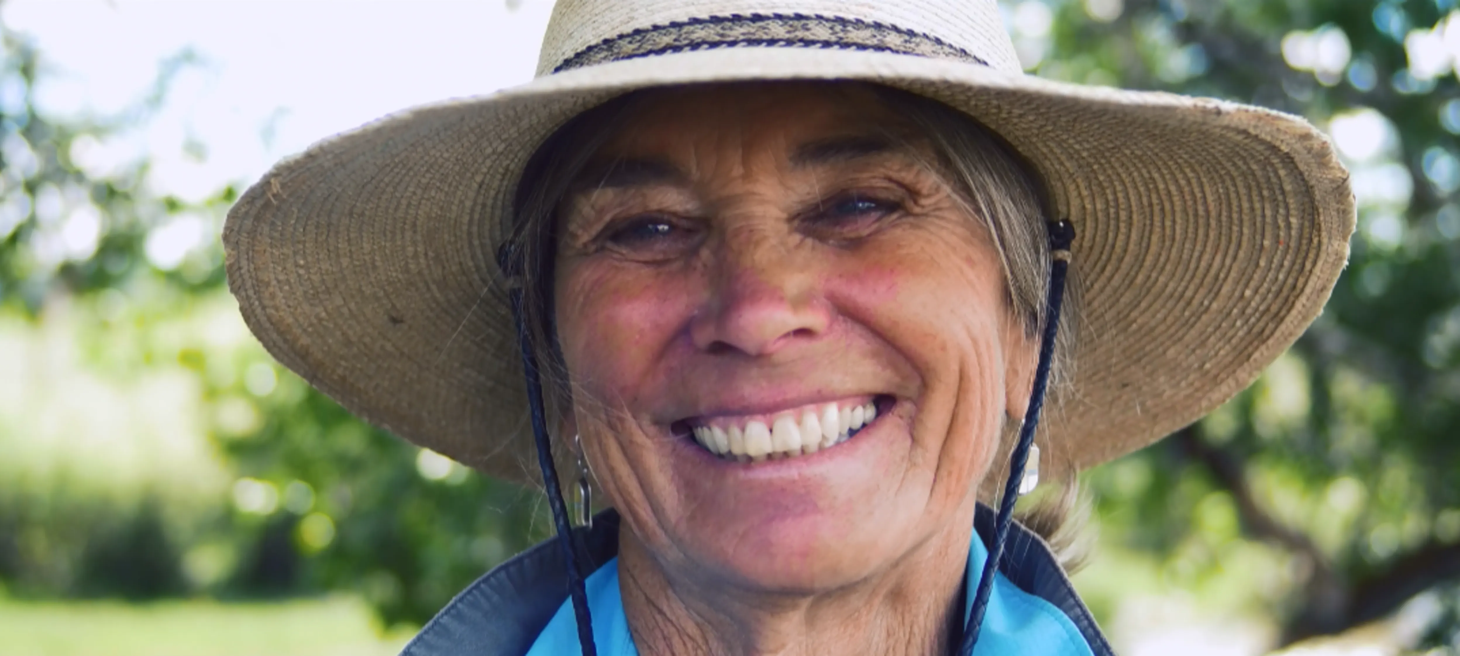Close-up of a woman wearing a brimmed hat smiling at the camera