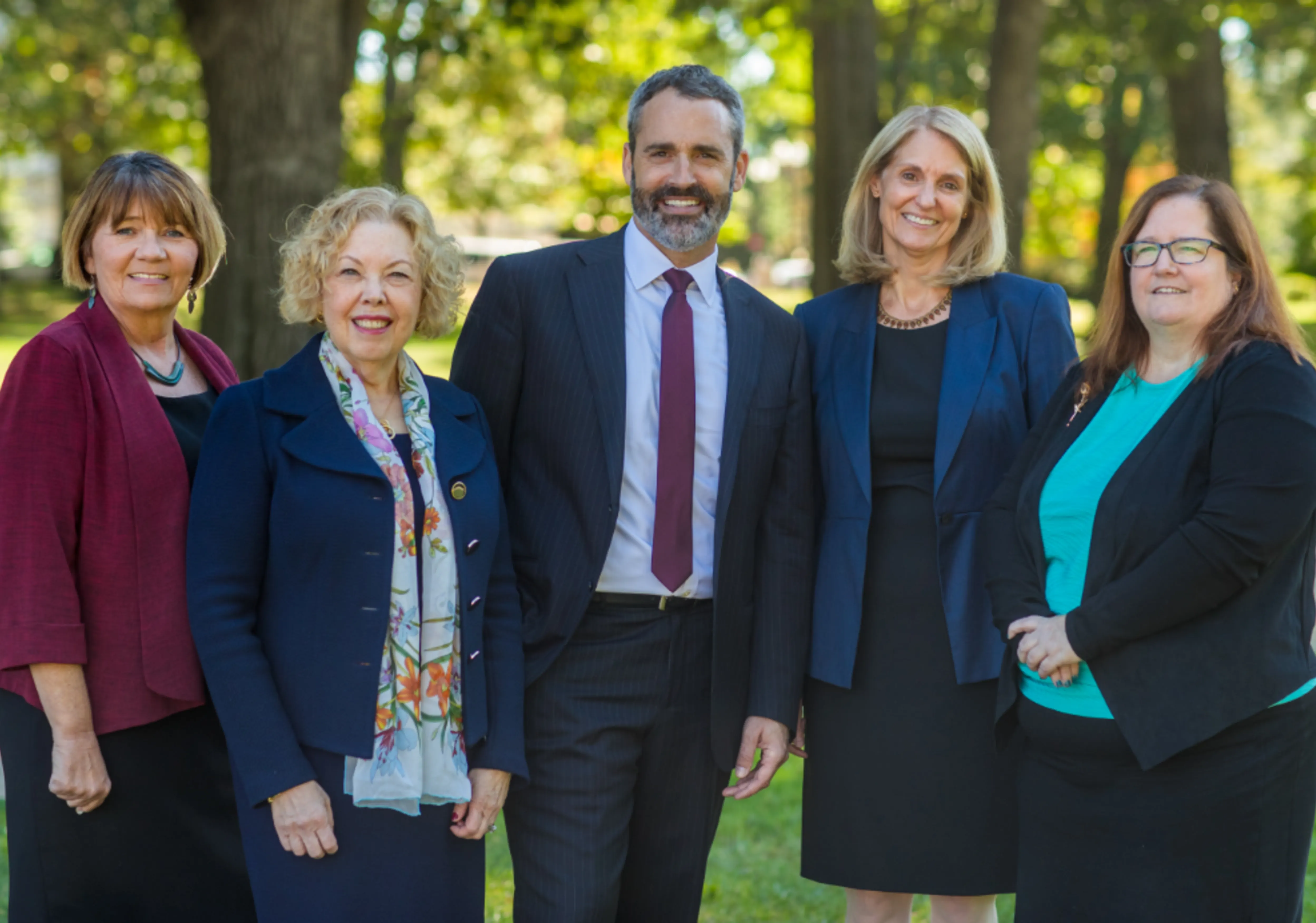 Five people standing in a row smiling.