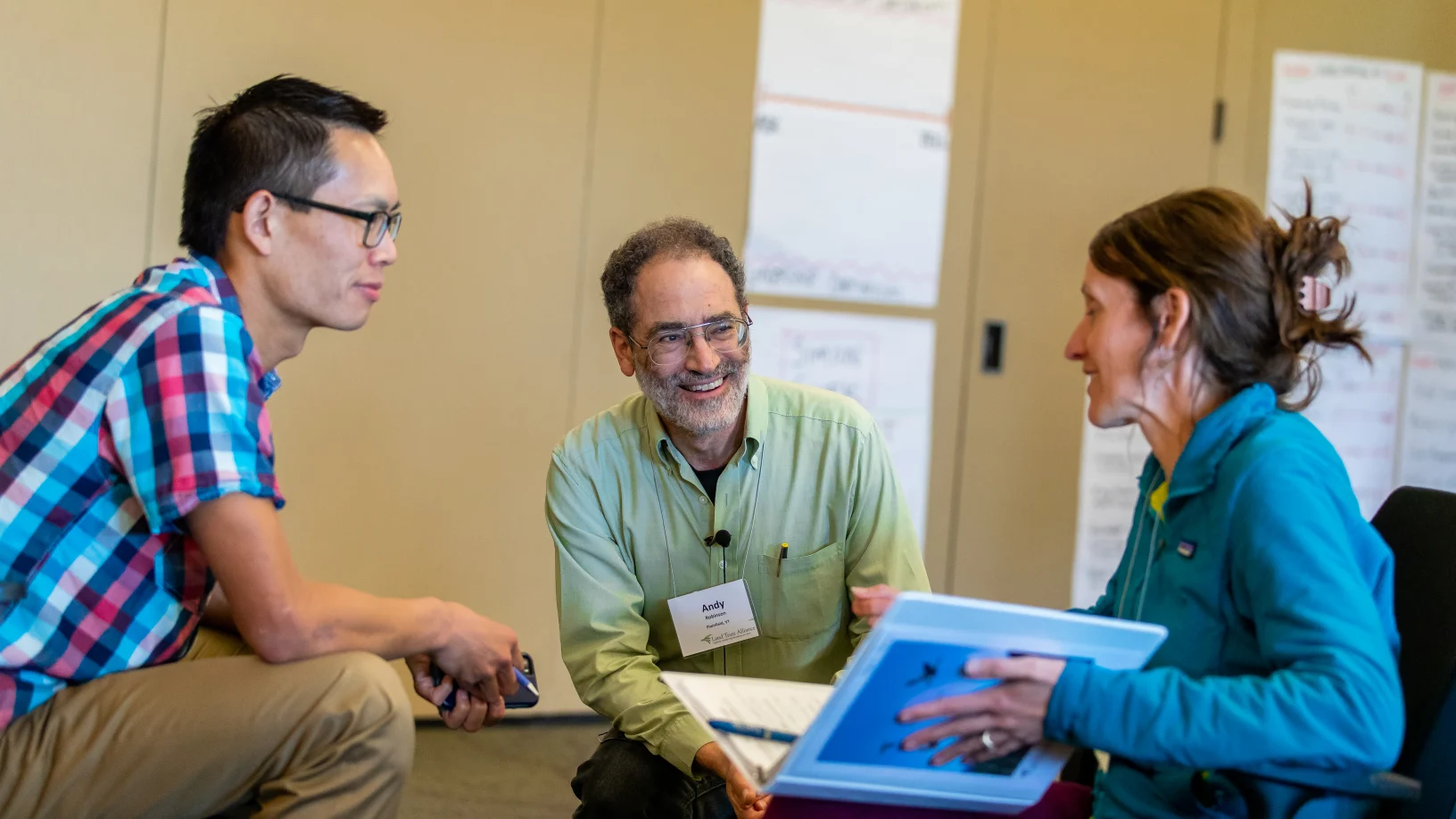 Three people sitting together with folders in a classroom