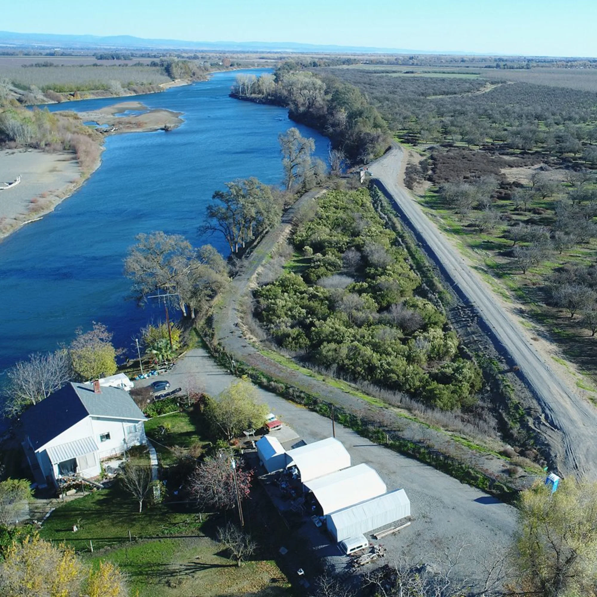 Above view of a highway surrounded by two rivers, with some buildings next to it and many trees.