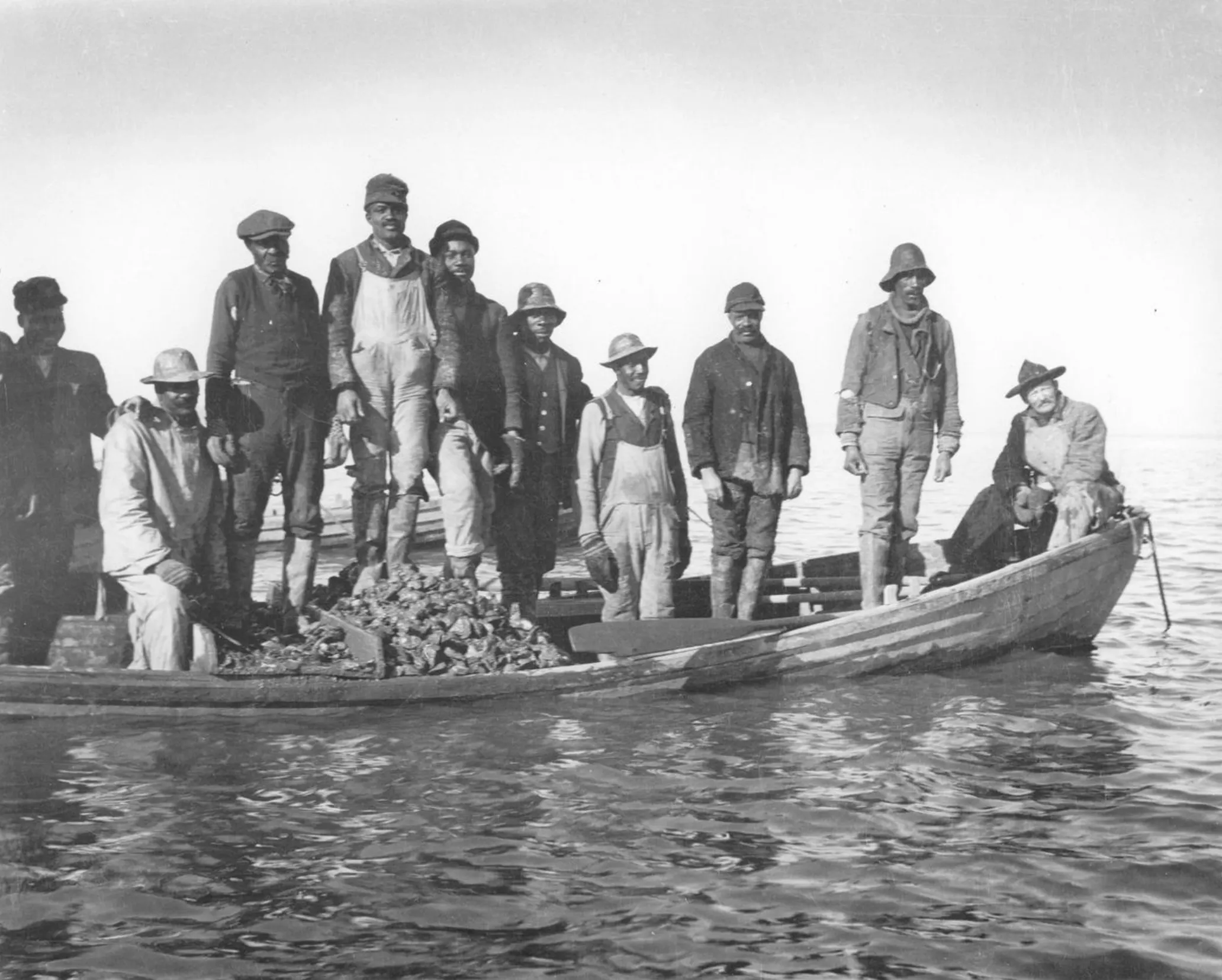 Ten Black men on a boat with oysters