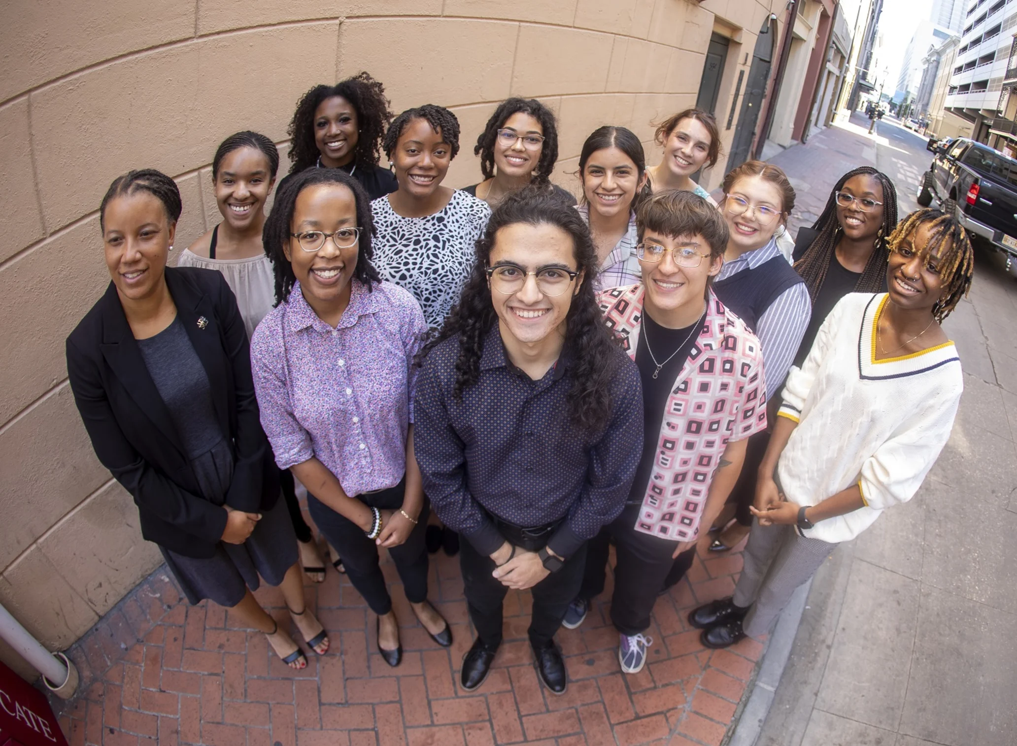 A diverse group of students smile up at the camera on a brick sidewalk in downtown New Orleans, Louisiana.