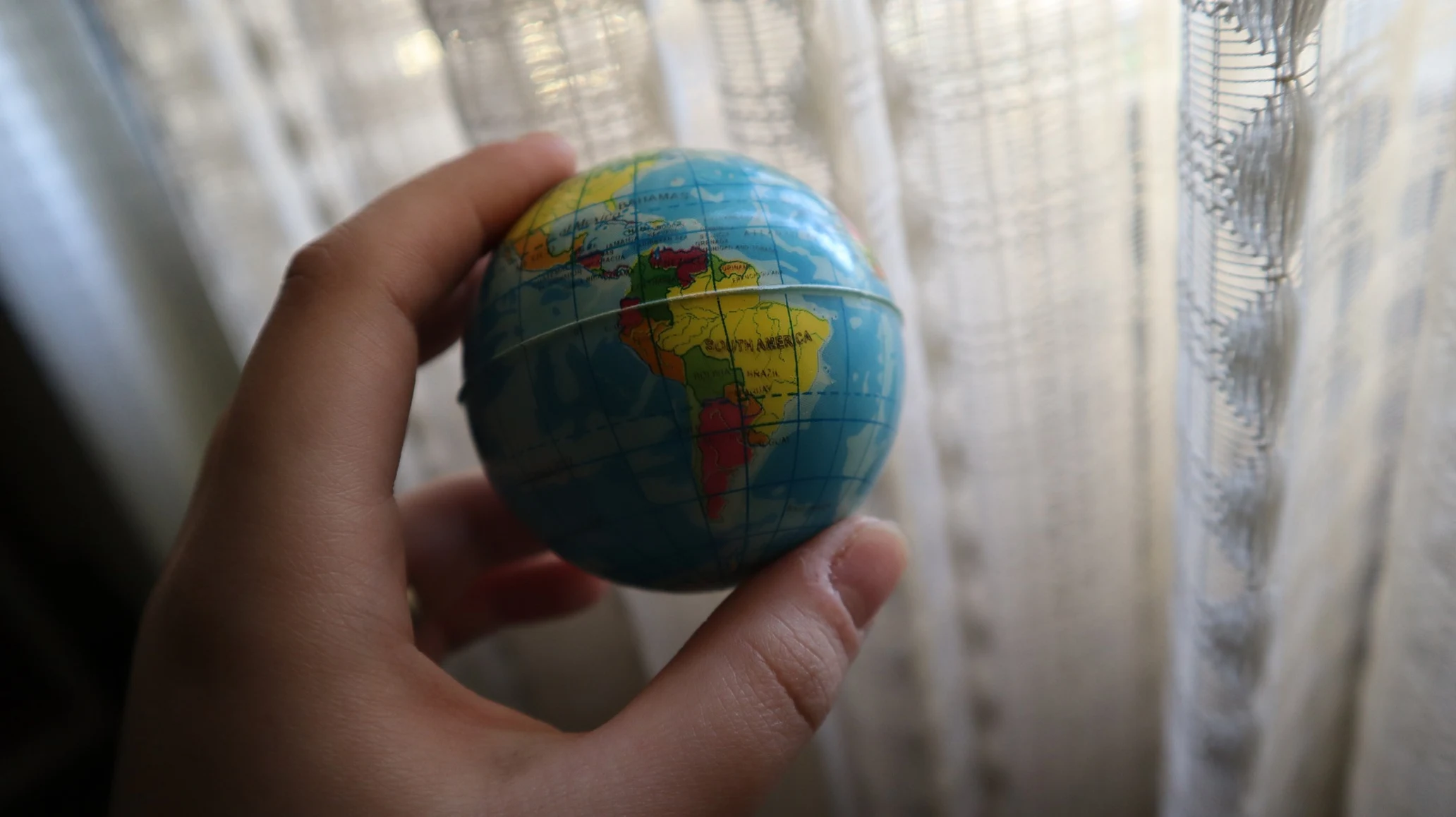 A hand holds a small globe