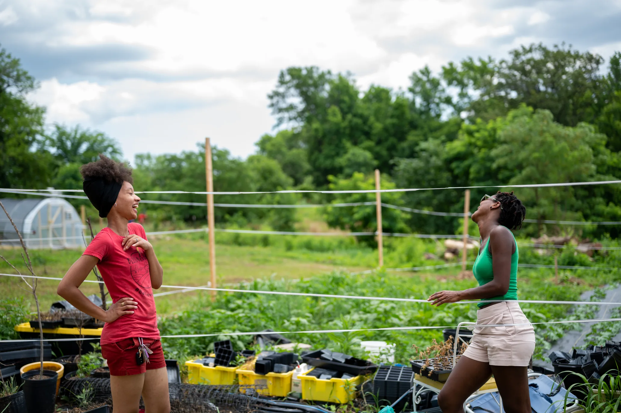 Two women standing in a garden laughing, with water spraying behind them.