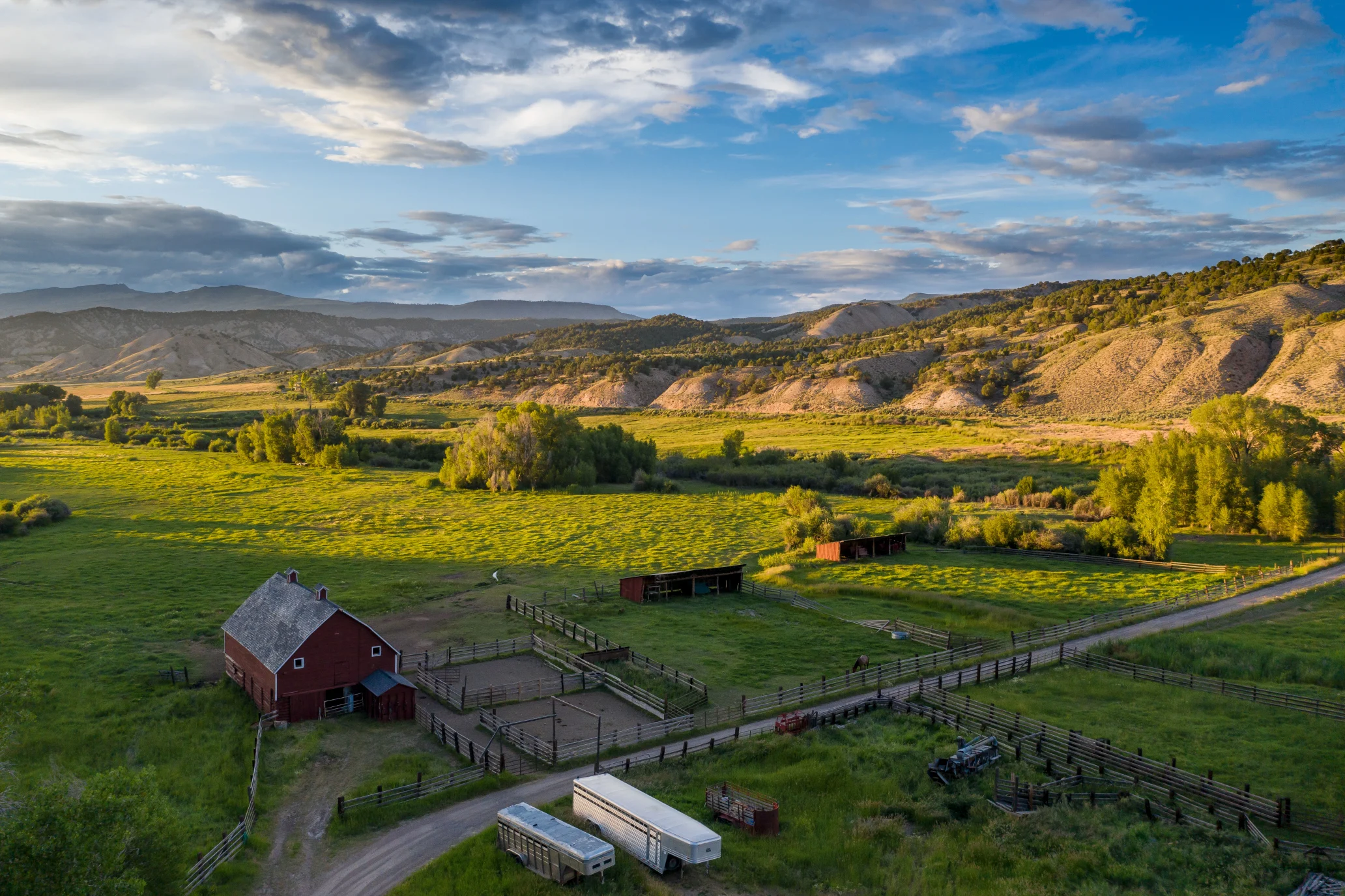 Aerial landscape with a barn and two trailers in front of hills