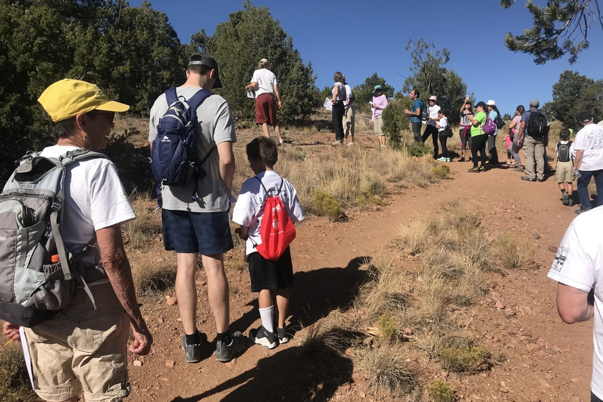 People of all ages line up on a trail to begin a scavenger hunt hike.