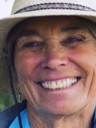 Close-up of a woman wearing a brimmed hat smiling at the camera