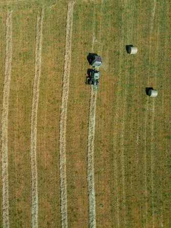 A field from above that has lines through it, with one line behind a tractor.