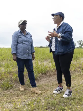 Two women standing in a field chatting.