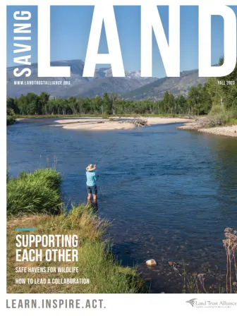 Saving Land magazine cover with a person with their back to us fishing in a body of water surrounded by mountains. The cover says "Saving Land, Fall 2023, WWW.LandTrustAlliance.org" at the top and later on the page "Supporting Each Other. Safe Havens for Wildlife. How to Lead a Collaboration." At the bottom it says "Learn. Inspire. Act" next to the Land Trust Alliance logo