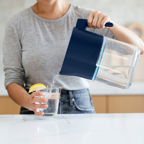 Photo of Larq Pitcher PureVis™ - Monaco Blue pouring water in glass (wide shot)