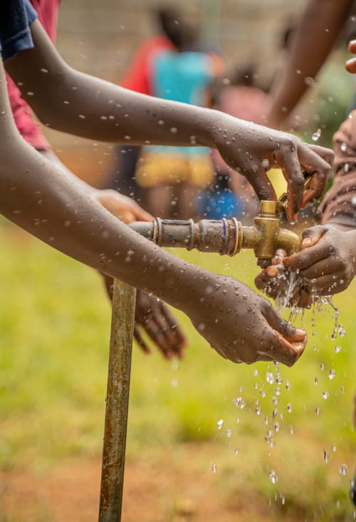 Hands around opened outdoor water valve