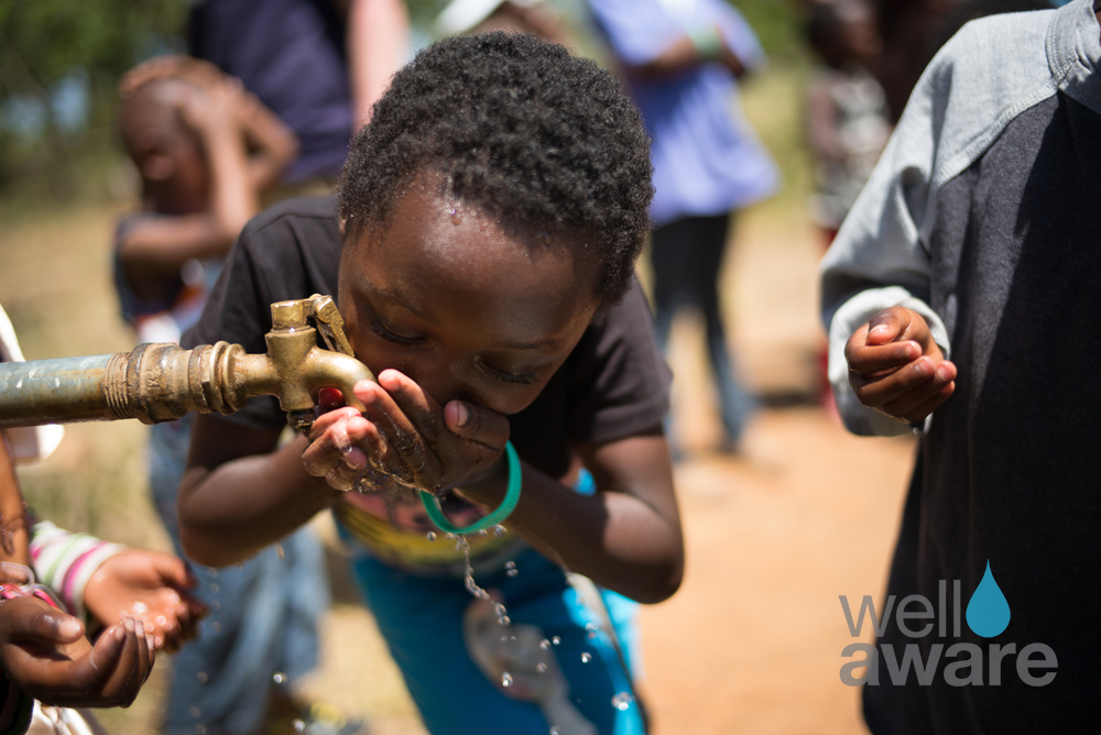 African boy drinking clean drinking water from fountain