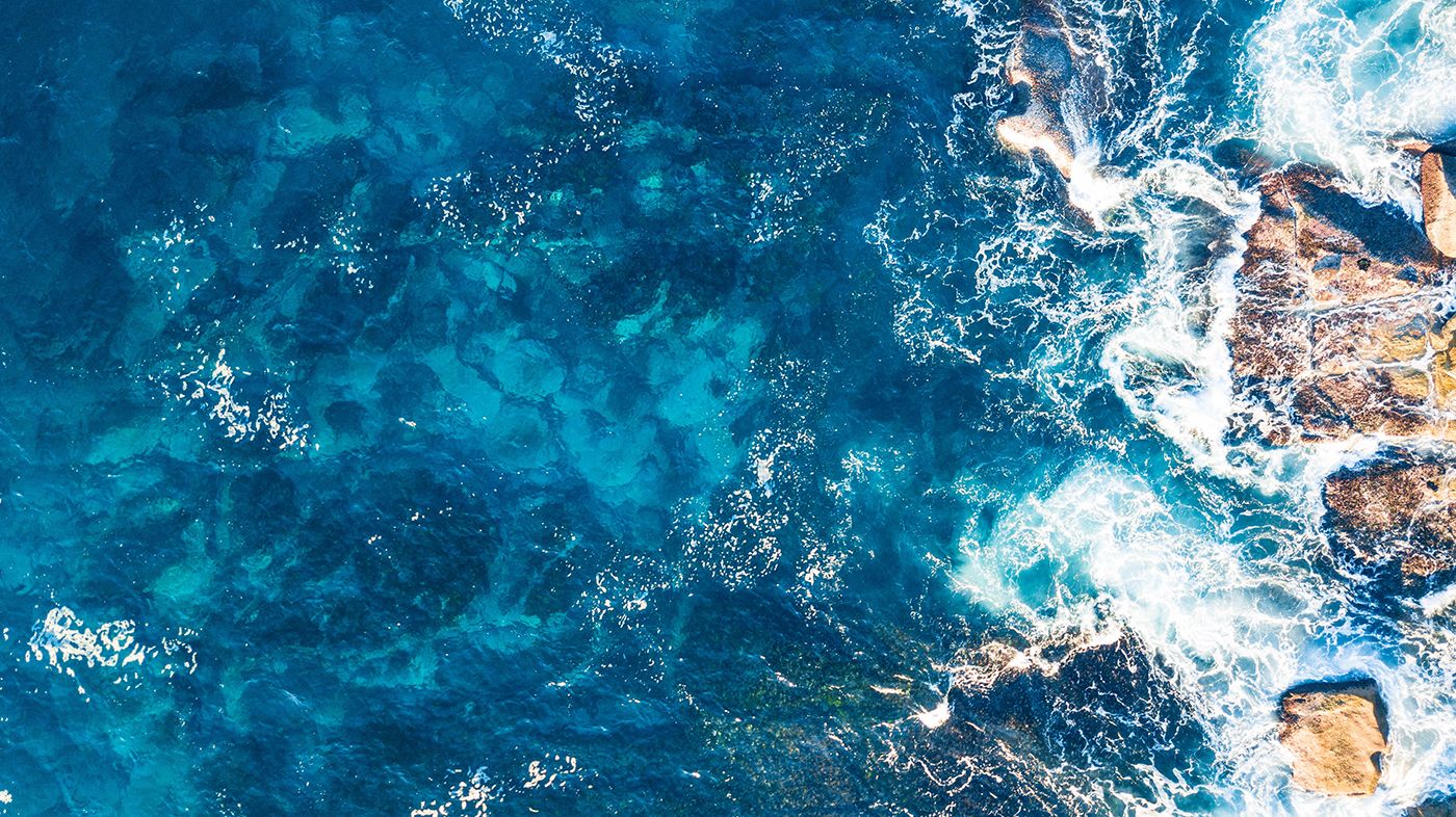 Aerial view of ocean crashing into rocks Photo by Oz MLCN on Unsplash
