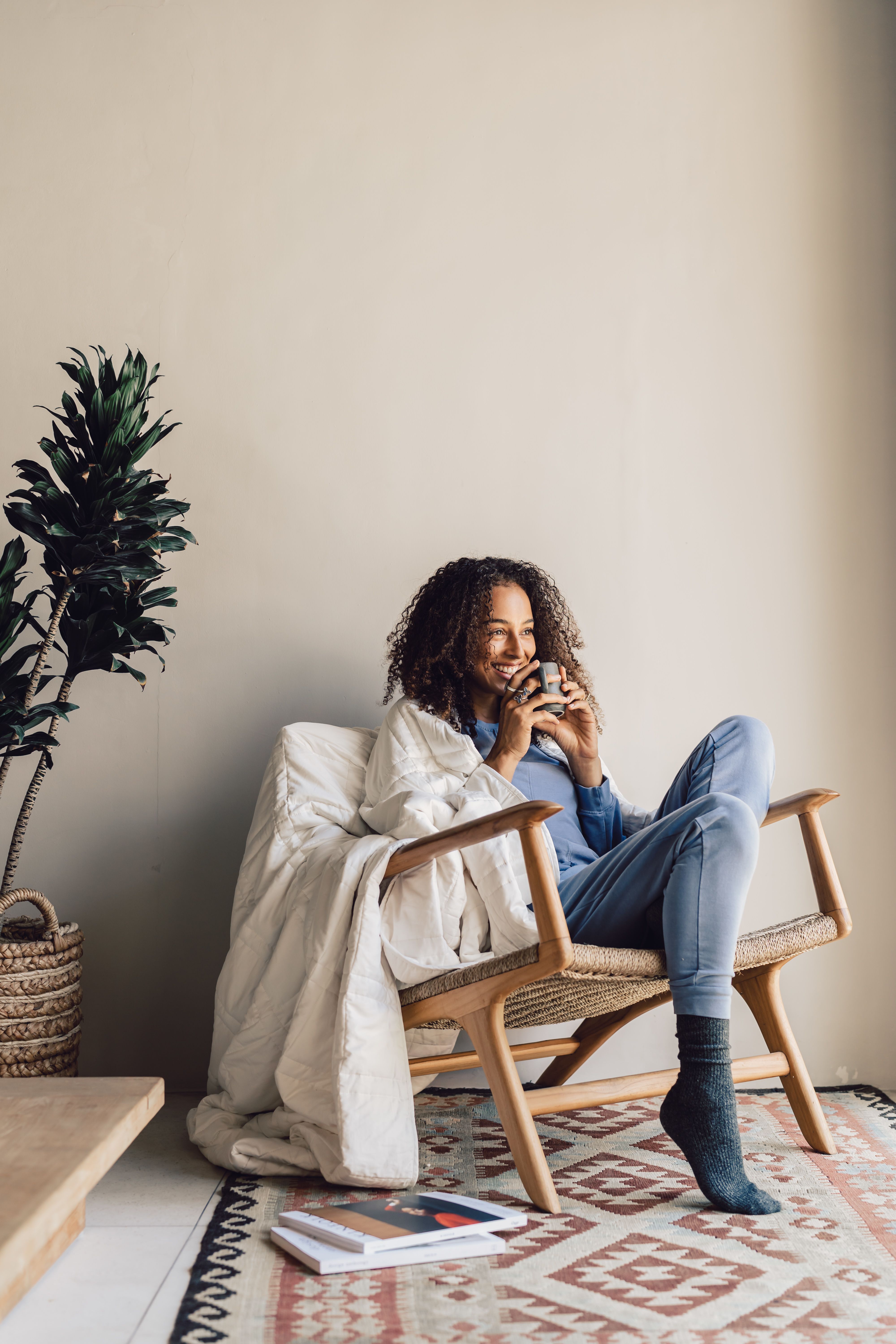 Model sitting in chair with Baloo Living weighted blanket 