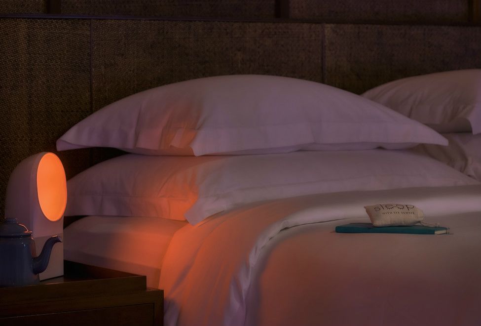 Dimly lit room with ambient lighting machine next to bed on nightstand at the Six Senses Hotel Resort and Spa