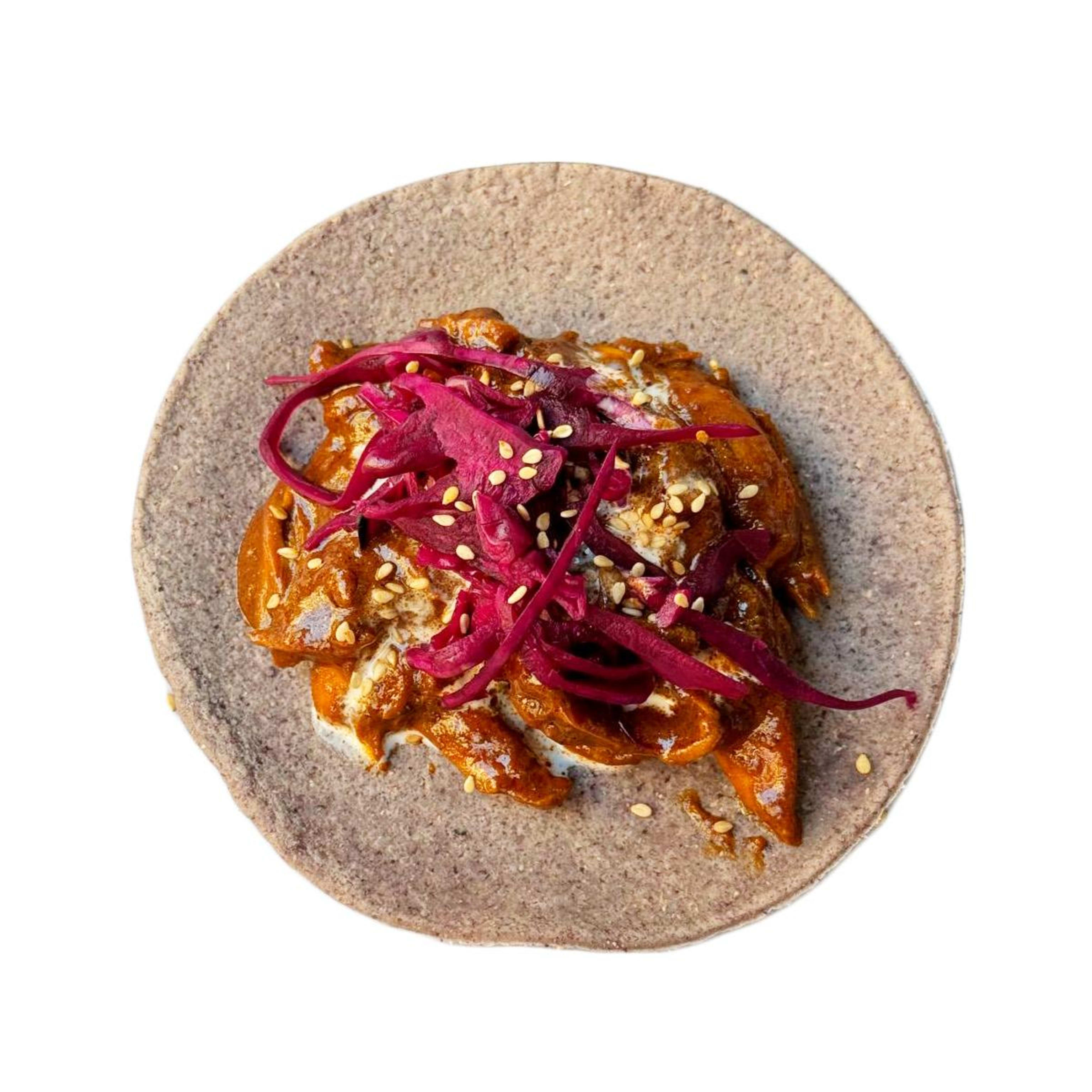 Taco de pollo con mole, sésamo, crema agria y col encurtida