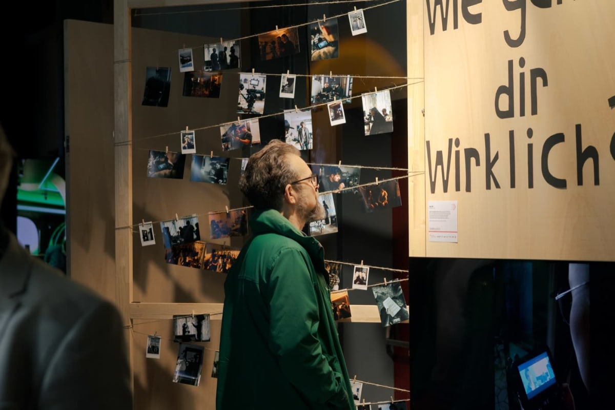 Besucher betrachten die Bilderwand