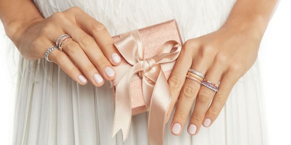 Model Wearing Multiple Wedding Rings Holding Gift Box'