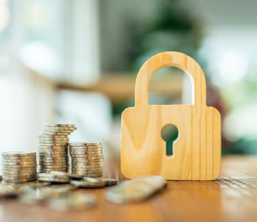 Pile of coins on a table next to a locket made of wood