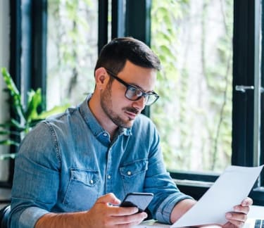 Man holding a mobile and a document