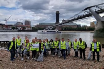 Group of people in hi-vis jackets collecting rubbish from a riverbank